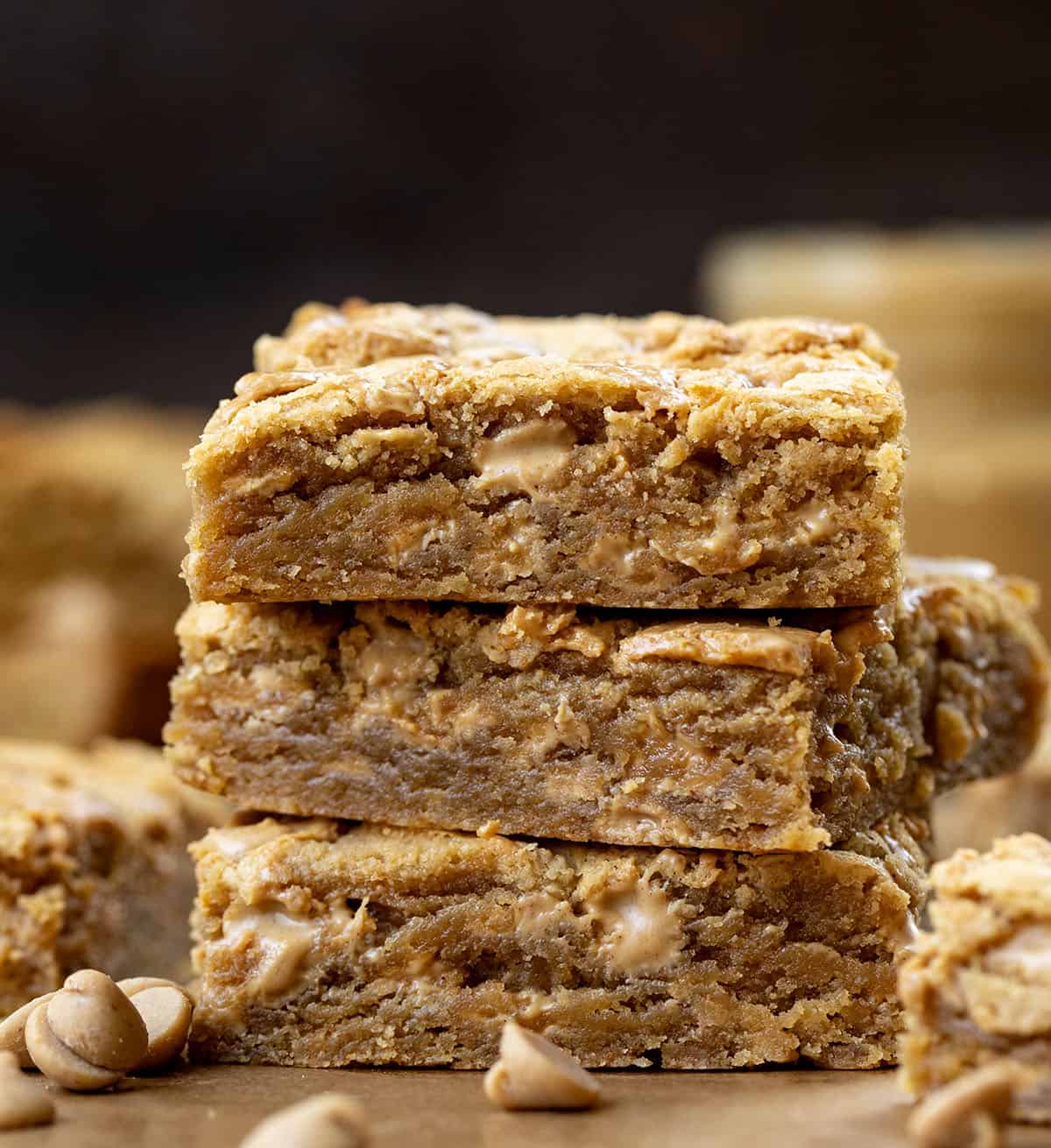 Stack of Peanut Butter Overload Blondies on a wooden table with peanut butter.