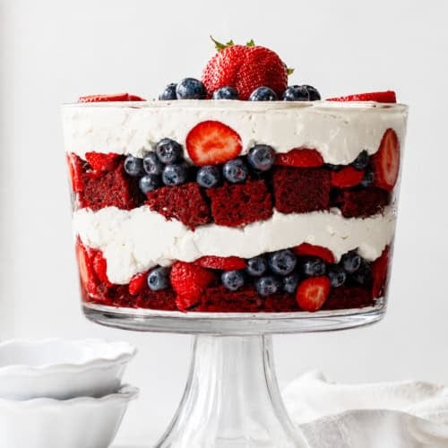 Looking at a Red Velvet Berry Trifle on a white counter top with white dishes and towel.