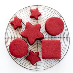 Red Velvet Cut-Out Sugar Cookies on a cooling rack on a white table.