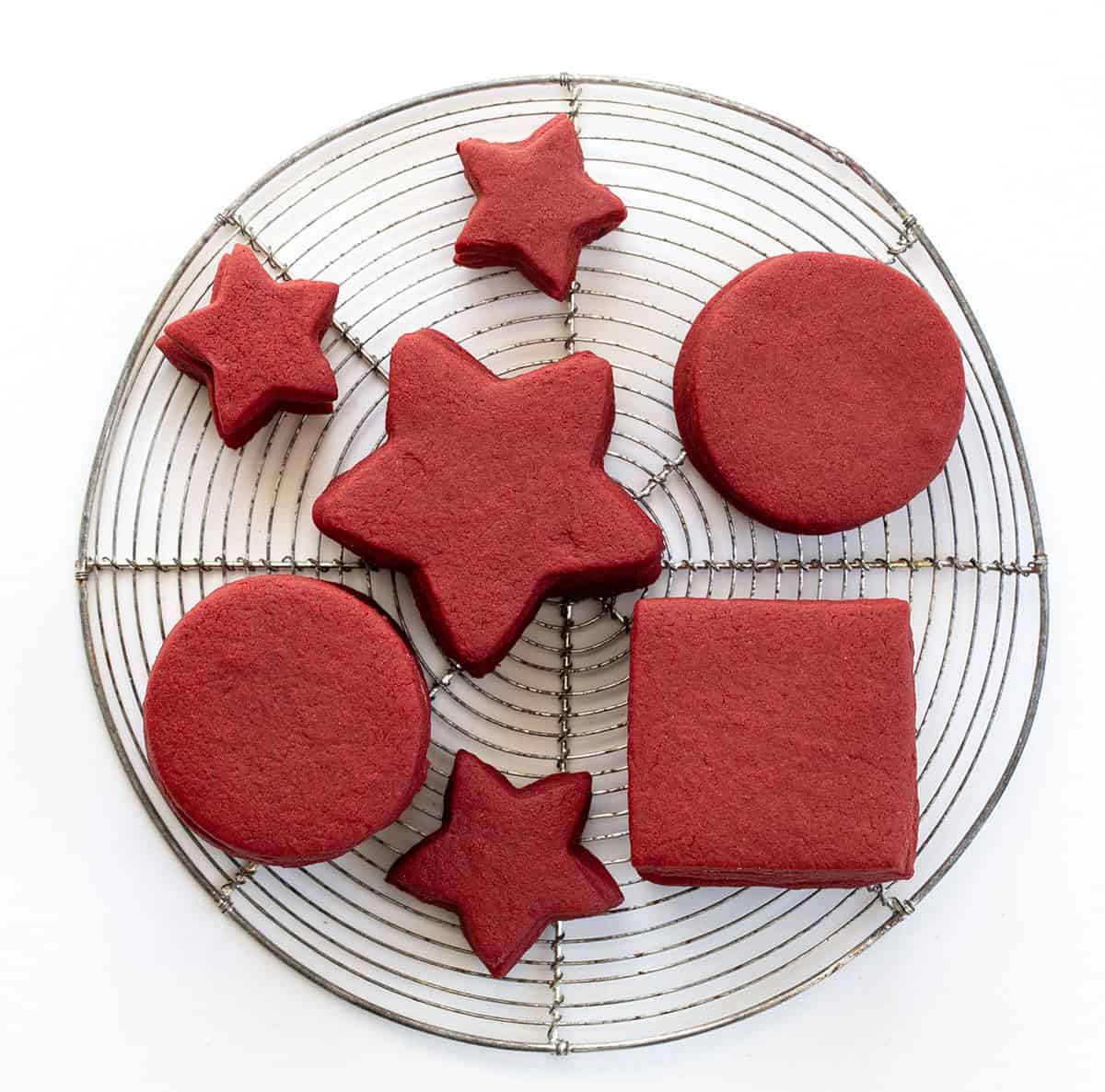 Red Velvet Cut-Out Sugar Cookies on a cooling rack on a white table.