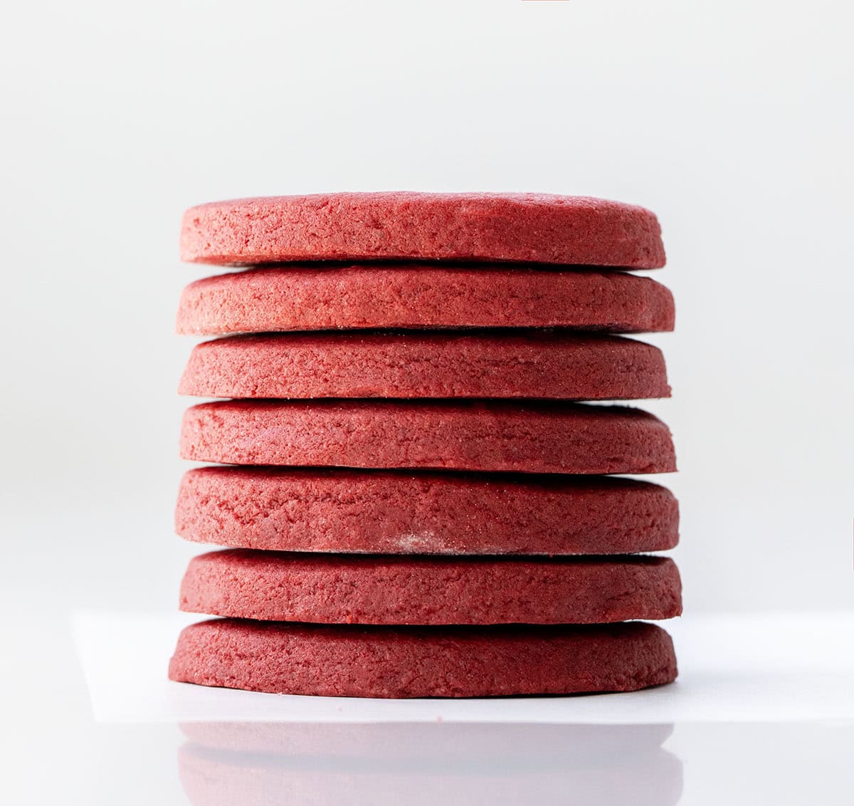 Stack of round Red Velvet Cut-Out Sugar Cookies on a white table.