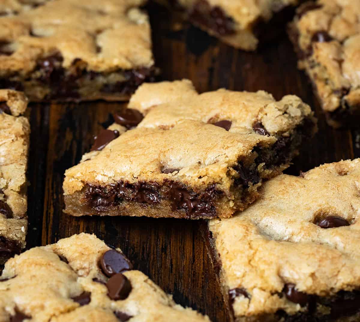 These Sheet Pan Chocolate Chip Cookies are an easy way to make a big batch of soft, chewy chocolate chip cookies in one pan. Thick, buttery, and loaded with chocolate chips, they bake up golden on the edges with a soft center in every bite. Close up of individual cut squares of Sheet Pan Chocolate Chip Cookies.