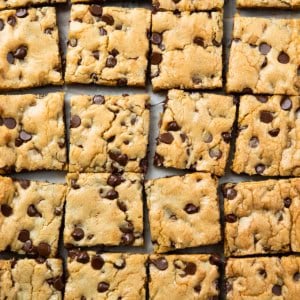 Sheet Pan Chocolate Chip Cookies cut into squares on tan parchment paper from overhead.