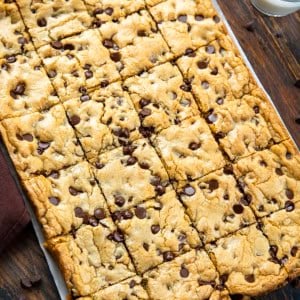 Sheet Pan Chocolate Chip Cookies on a wooden table with glass of milk.