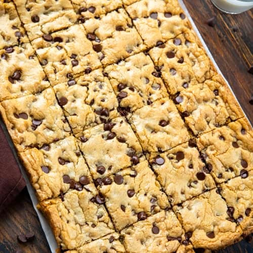 Sheet Pan Chocolate Chip Cookies on a wooden table with glass of milk.