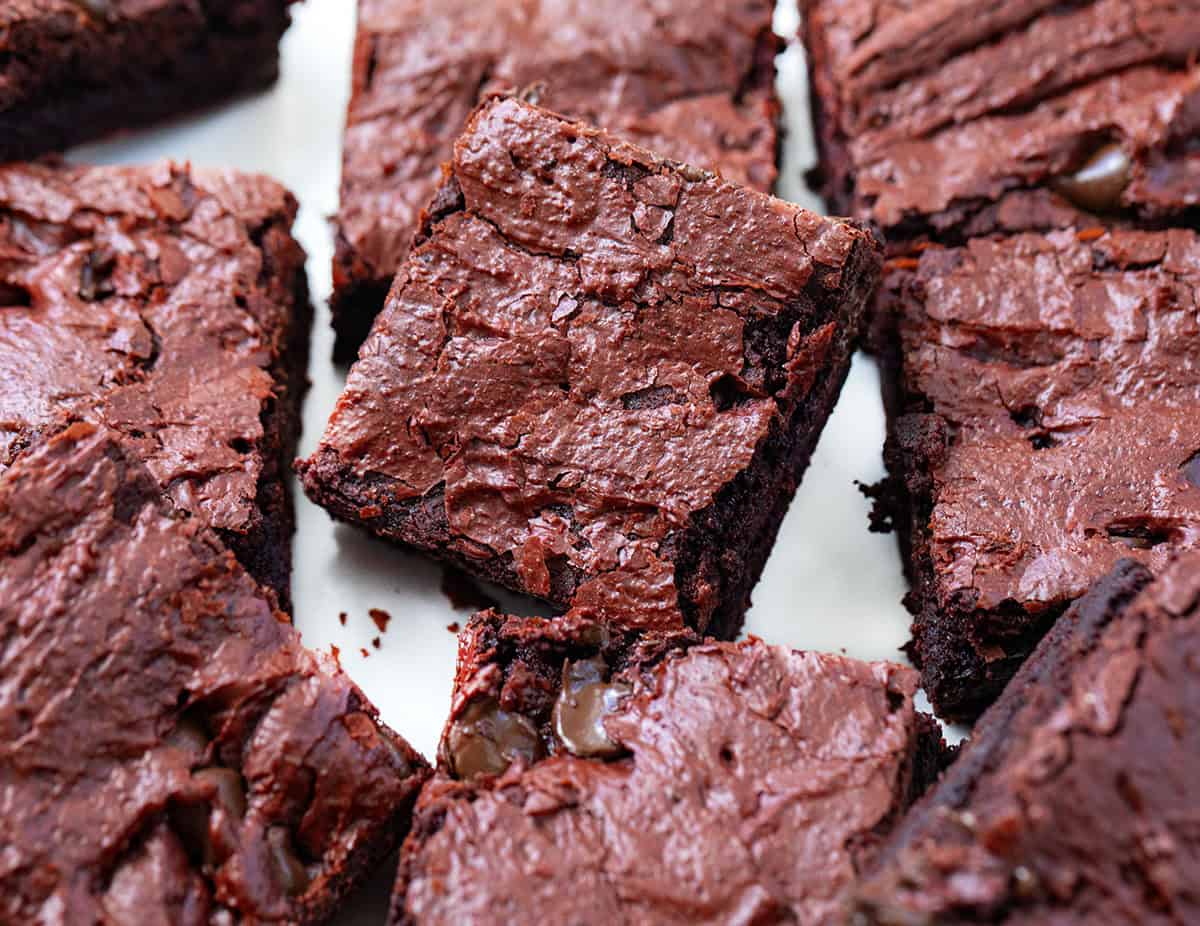 Close up of Red Velvet Sheet Pan Brownies cut into squares on a white table.