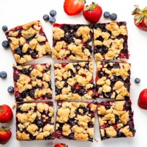 Strawberry Blueberry Crumble Bars cut into squares on a white table from overhead.