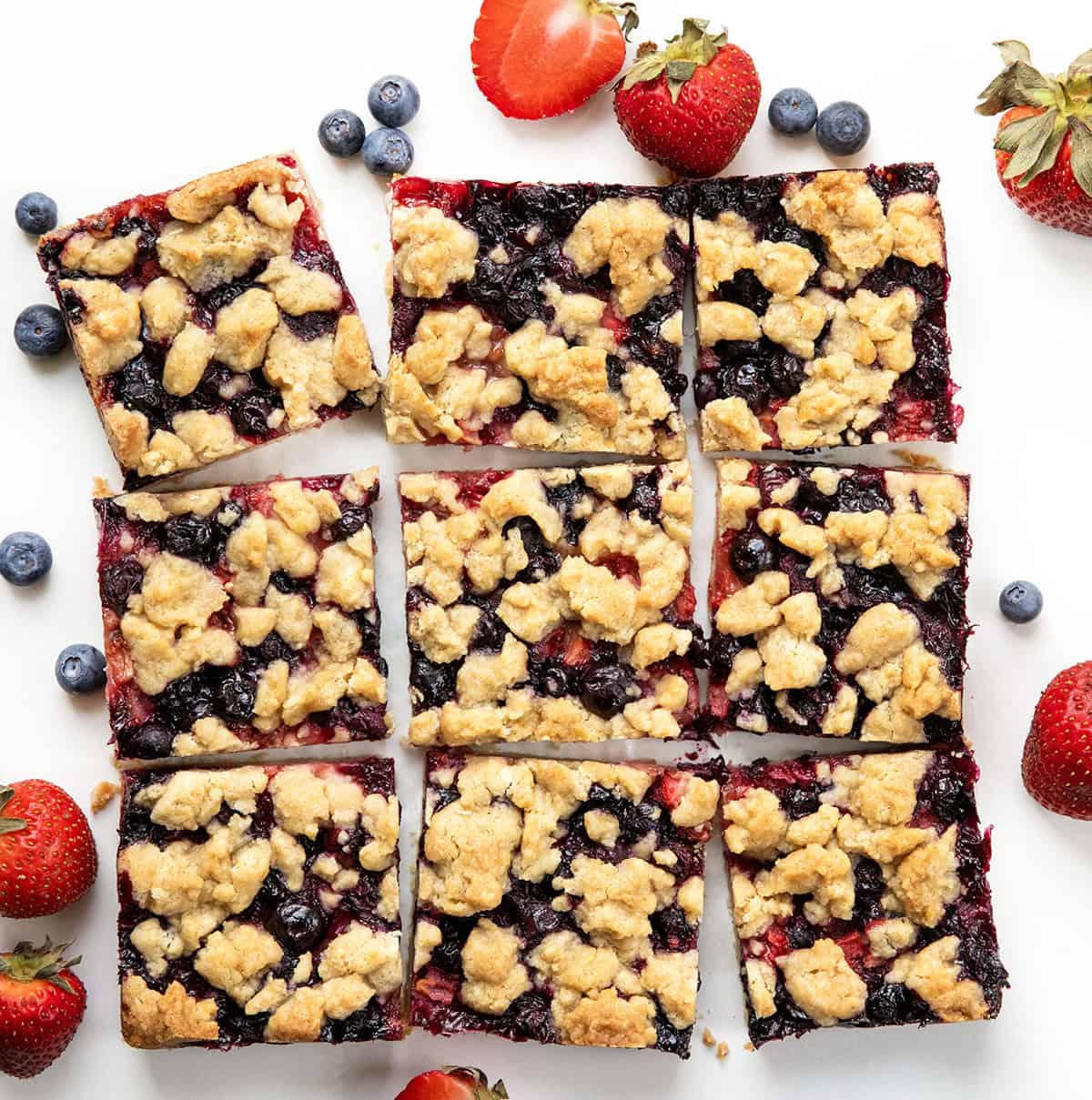 Strawberry Blueberry Crumble Bars cut into squares on a white table from overhead.