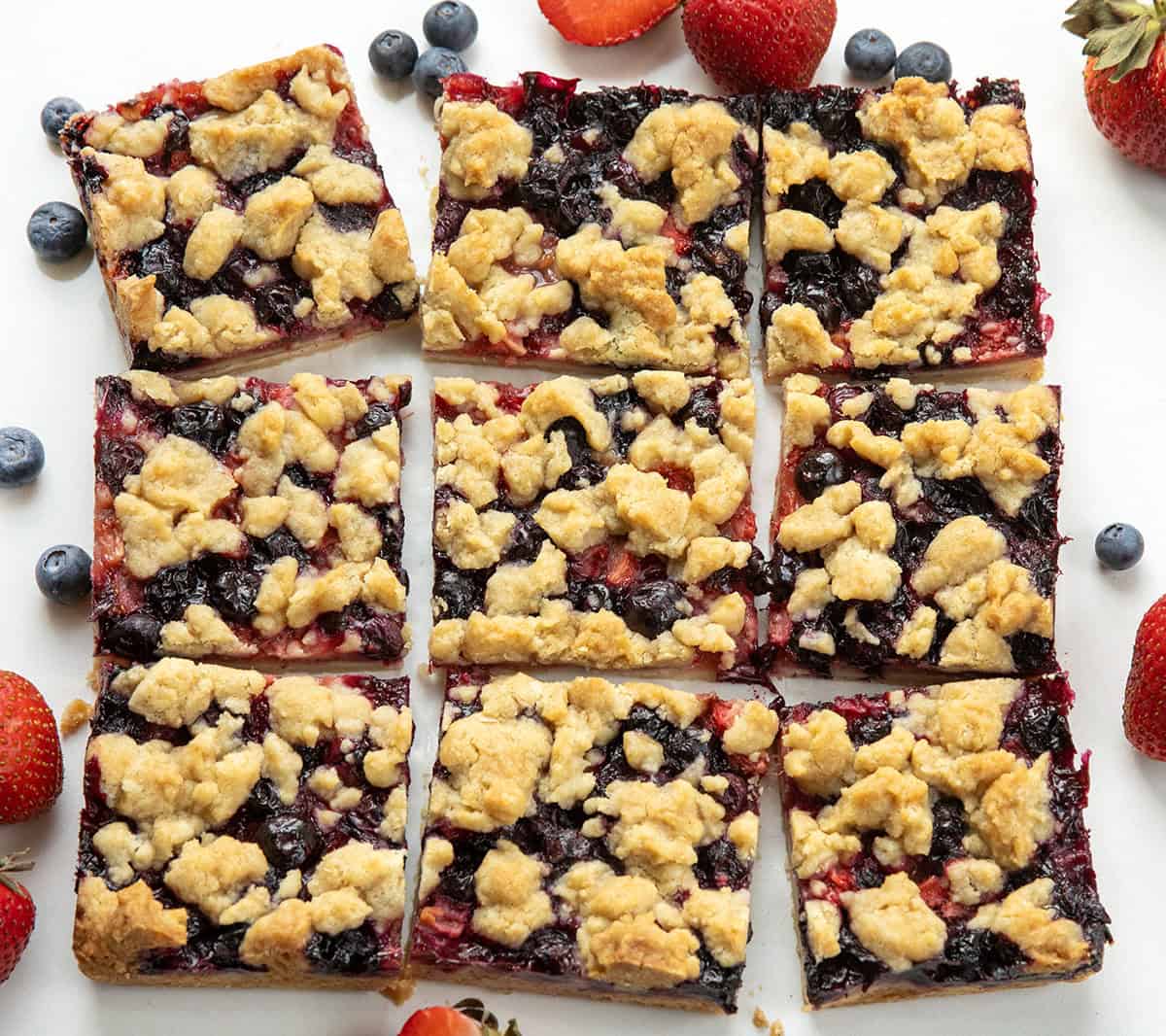 Strawberry Blueberry Crumble Bars cut into squares on a white table from overhead.
