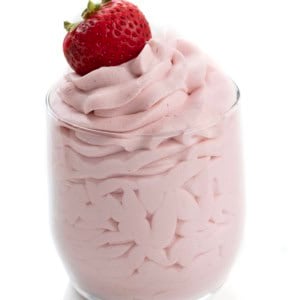 Glass of piped Strawberry Stabilized Whipped Cream with a strawberry on top.