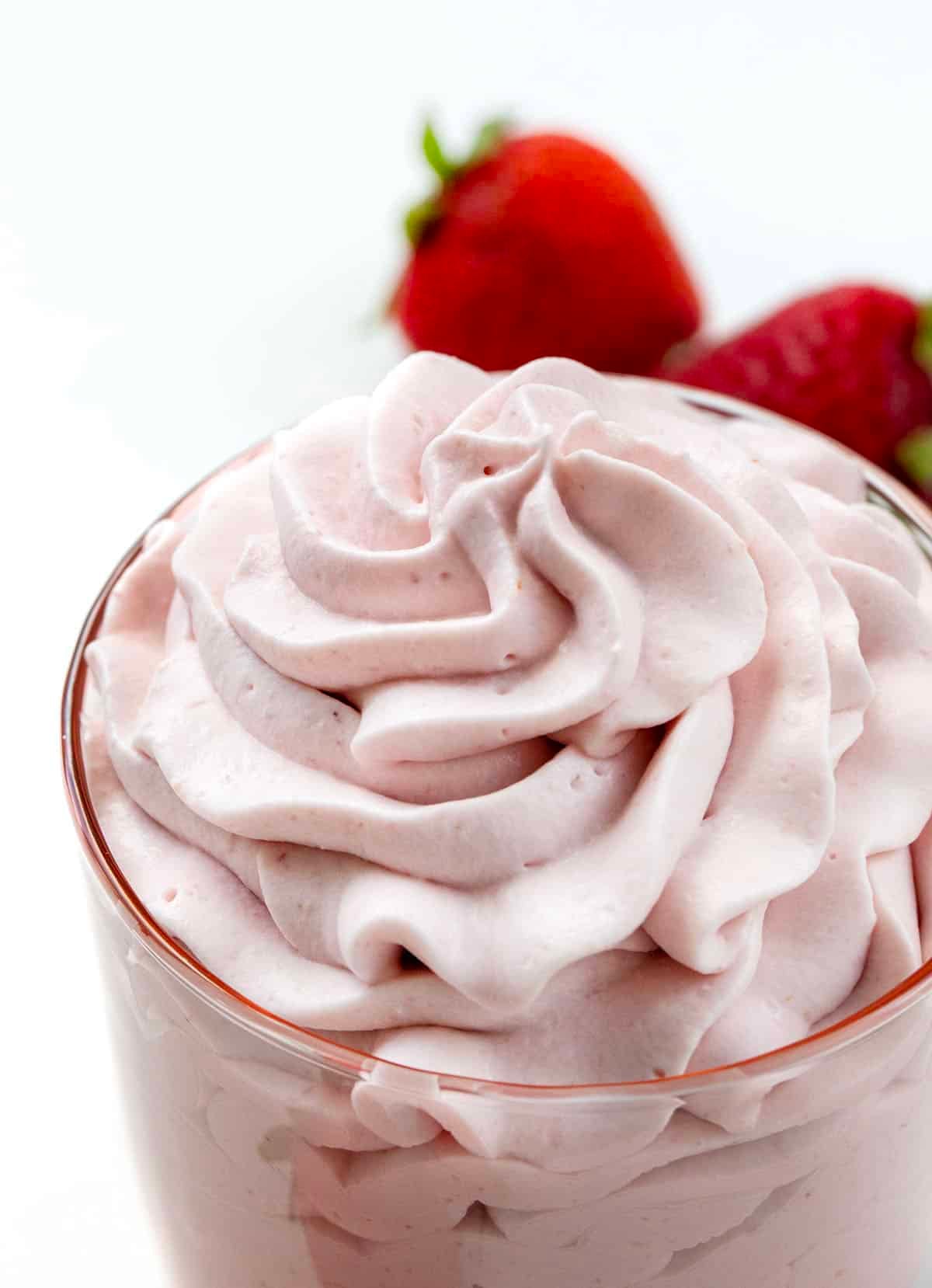 Close up of Strawberry Stabilized Whipped Cream and fresh strawberries.