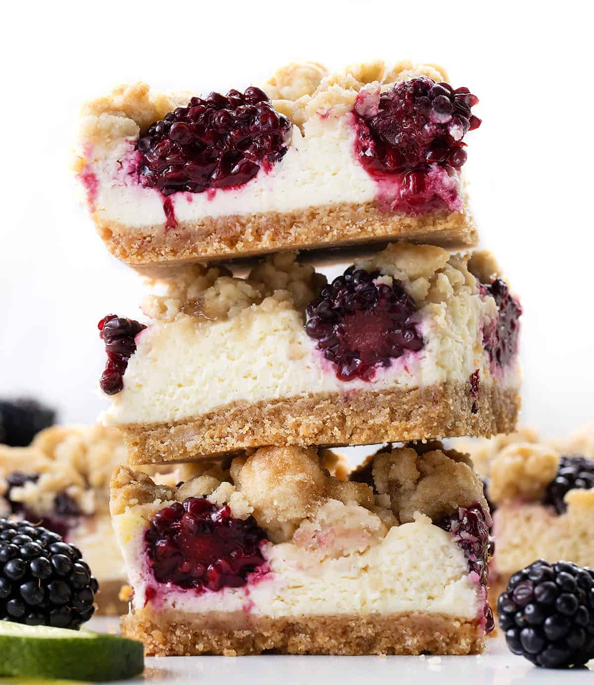 Stack of Blackberry Lime Cheesecake Bars on a white table with fresh blackberries and fresh cut lime Stack of Blackberry Lime Cheesecake Bars on a white table with fresh blackberries and fresh cut lime.