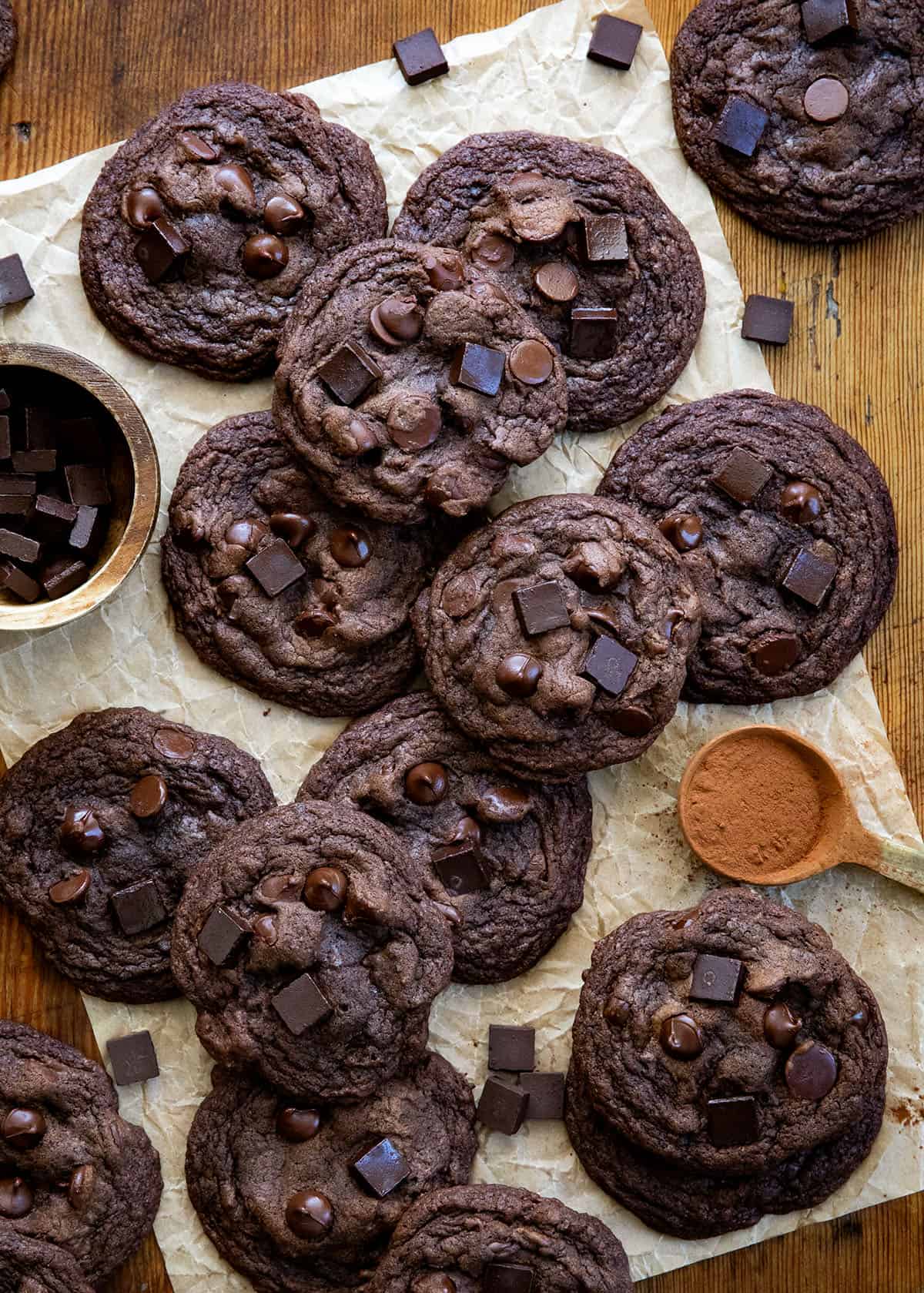 Bloomed Cocoa Chocolate Chip Cookies on a wooden table with cocoa and chocolate chunks from overhead Bloomed Cocoa Chocolate Chip Cookies on a wooden table with cocoa and chocolate chunks from overhead.