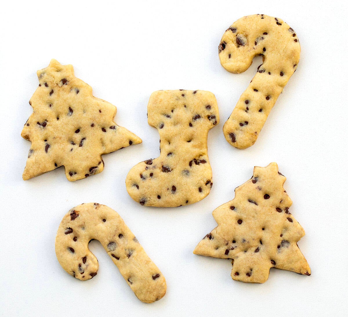 Christmas themed Chocolate Chip Cut-Out Cookies in stockings, trees, and candy canes on a white table Christmas themed Chocolate Chip Cut-Out Cookies in stockings, trees, and candy canes on a white table.