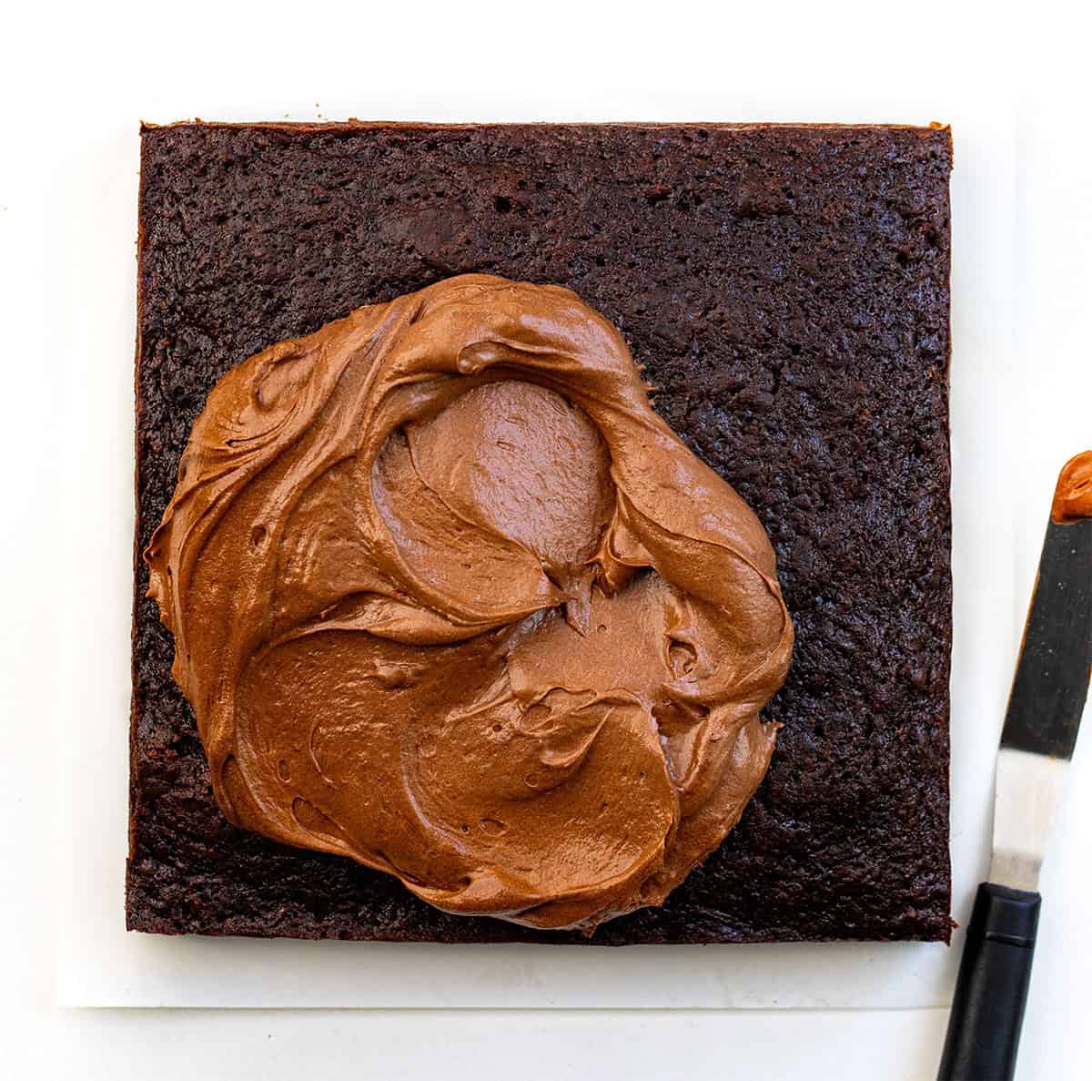 Chocolate Zucchini Snack Cake with brownie chocolate frosting on top about to be spread Chocolate Zucchini Snack Cake with brownie chocolate frosting on top about to be spread.