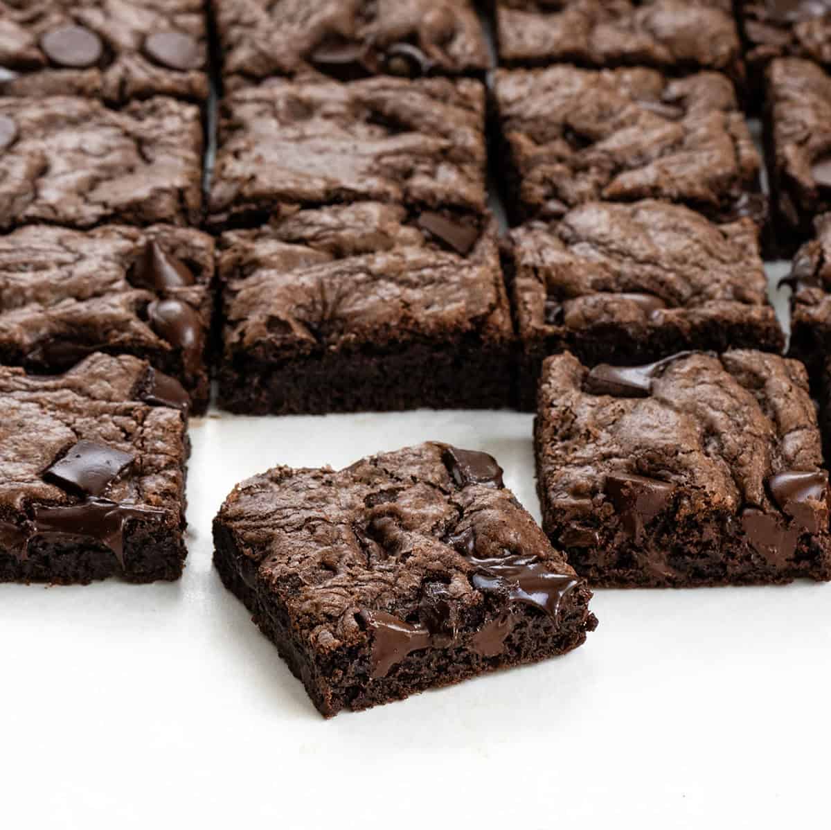 Double Chocolate Sheet Pan Cookies cut into squares with one cookie bar set apart from the rest Double Chocolate Sheet Pan Cookies cut into squares with one cookie bar set apart from the rest on a white counter.