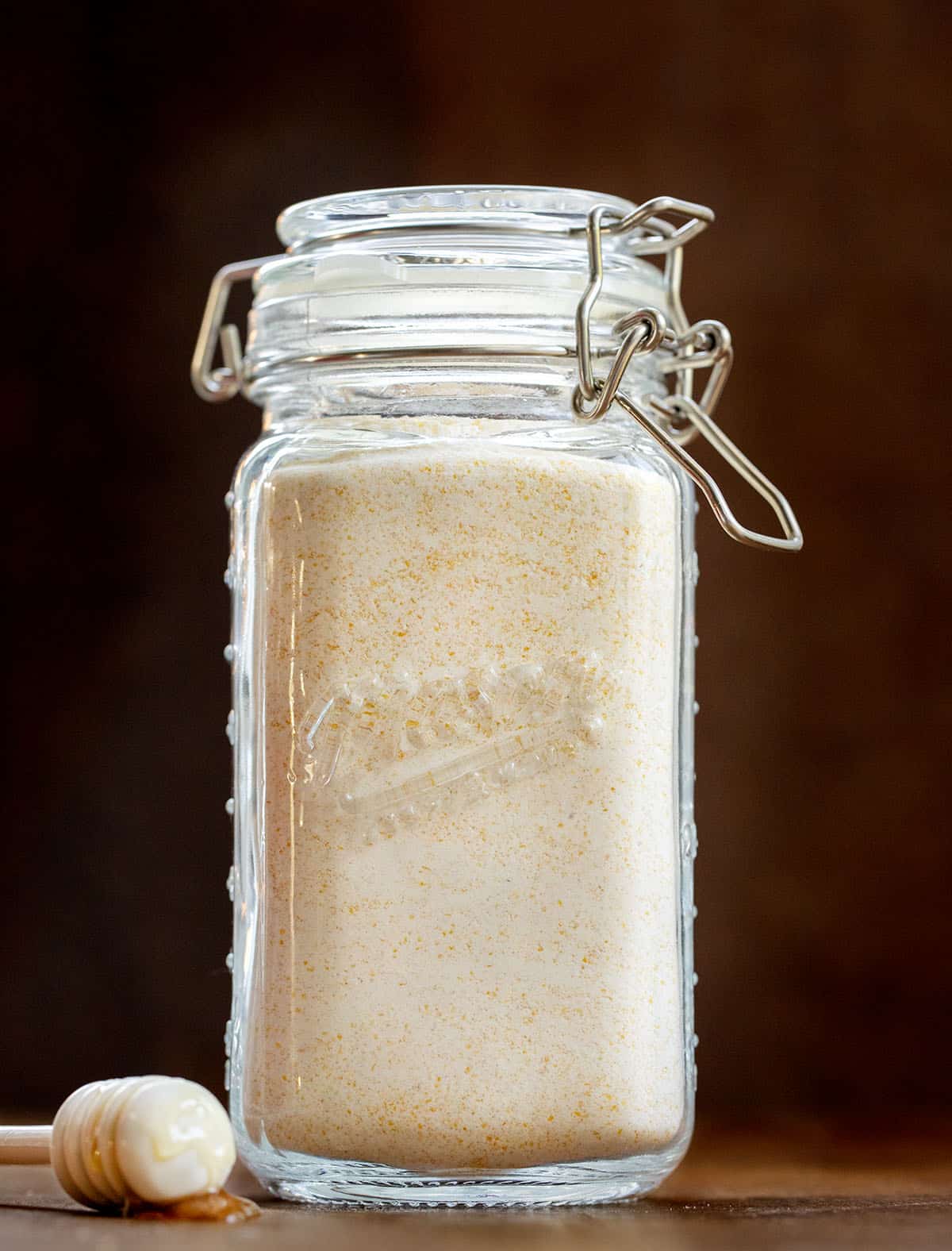 Glass jar filled with Homemade Cornbread Mix on a wooden table.
