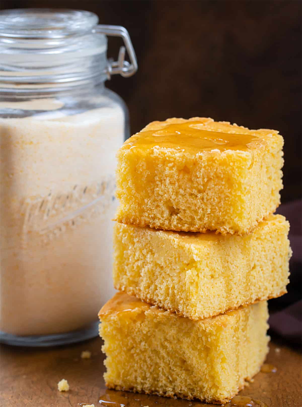 Jar of Homemade Cornbread Mix next to a stack of tender cornbread.