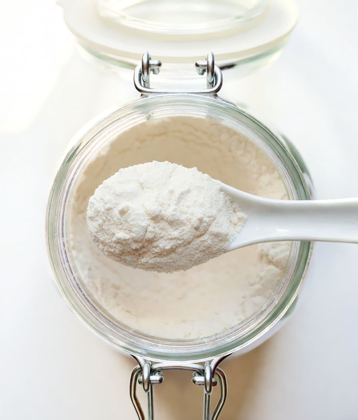 Scoop of Homemade Vanilla Pudding Mix being held above the jar Scoop of Homemade Vanilla Pudding Mix being held above the jar.