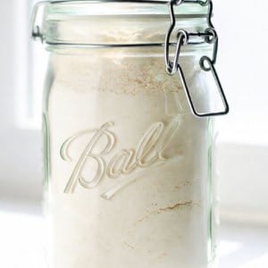 Jar of Homemade Vanilla Pudding Mix on a white counter in front of a window.