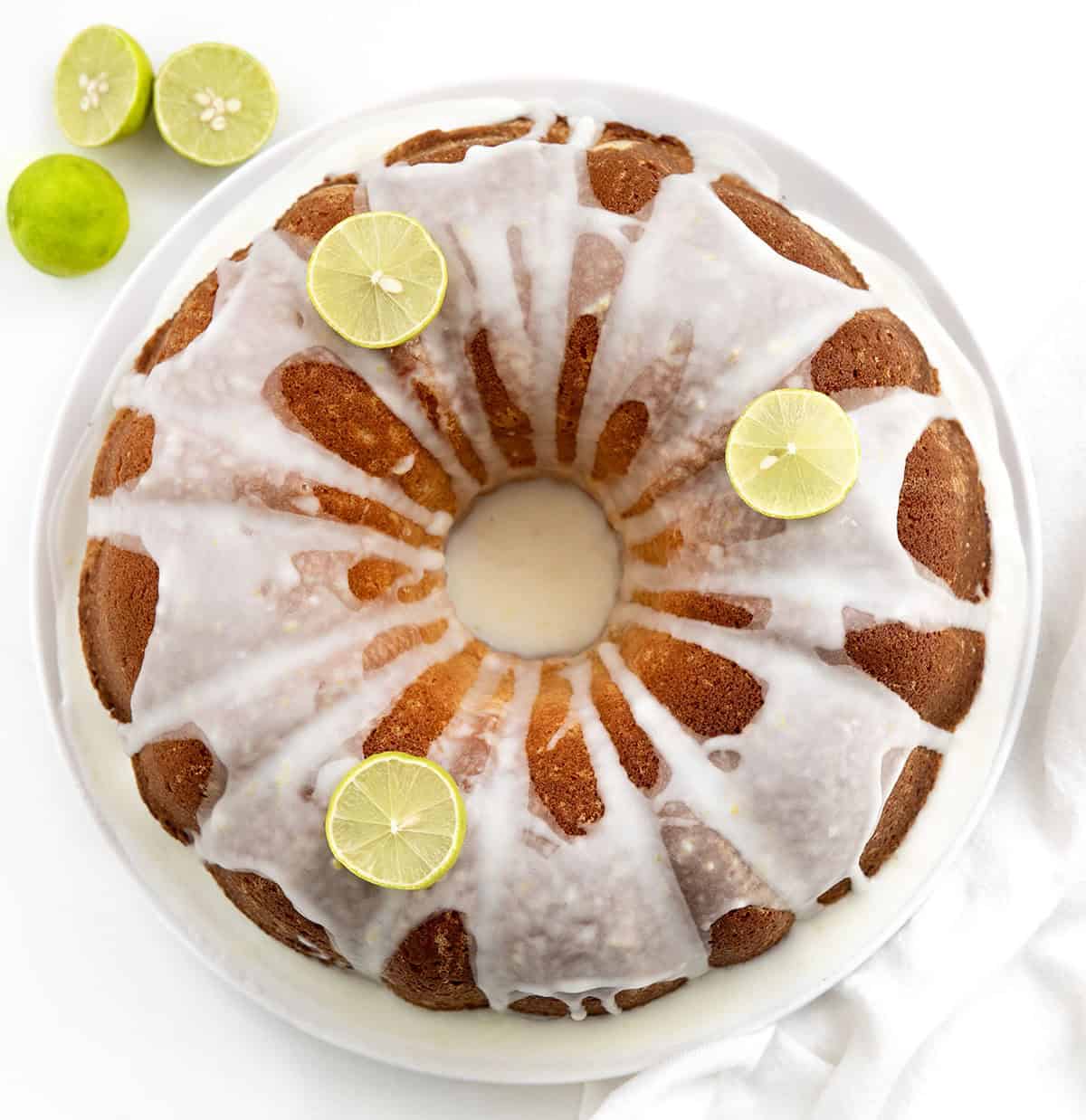 Whole Key Lime Pound Cake on a white platter on a white table from overhead Whole Key Lime Pound Cake on a white platter on a white table from overhead.