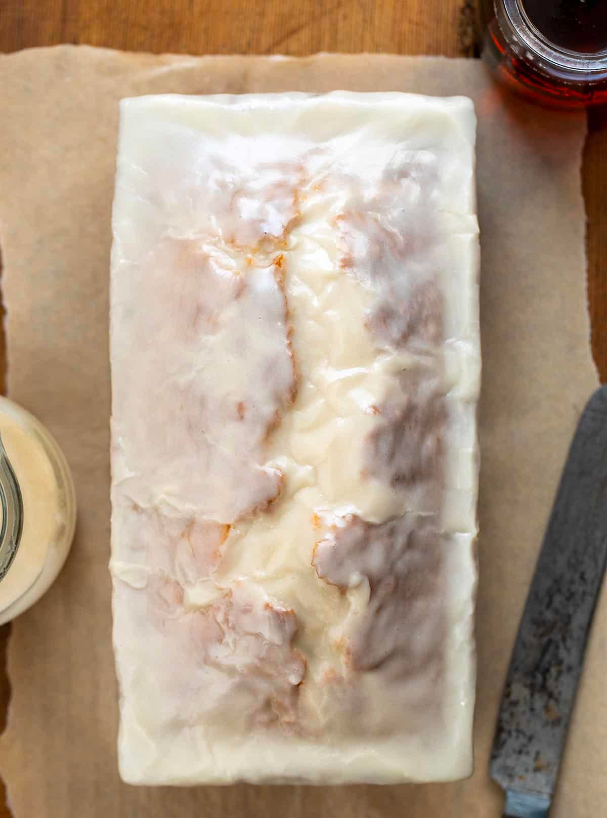 Maple Glazed Donut Bread on a piece of parchment paper on a wooden table from overhead.