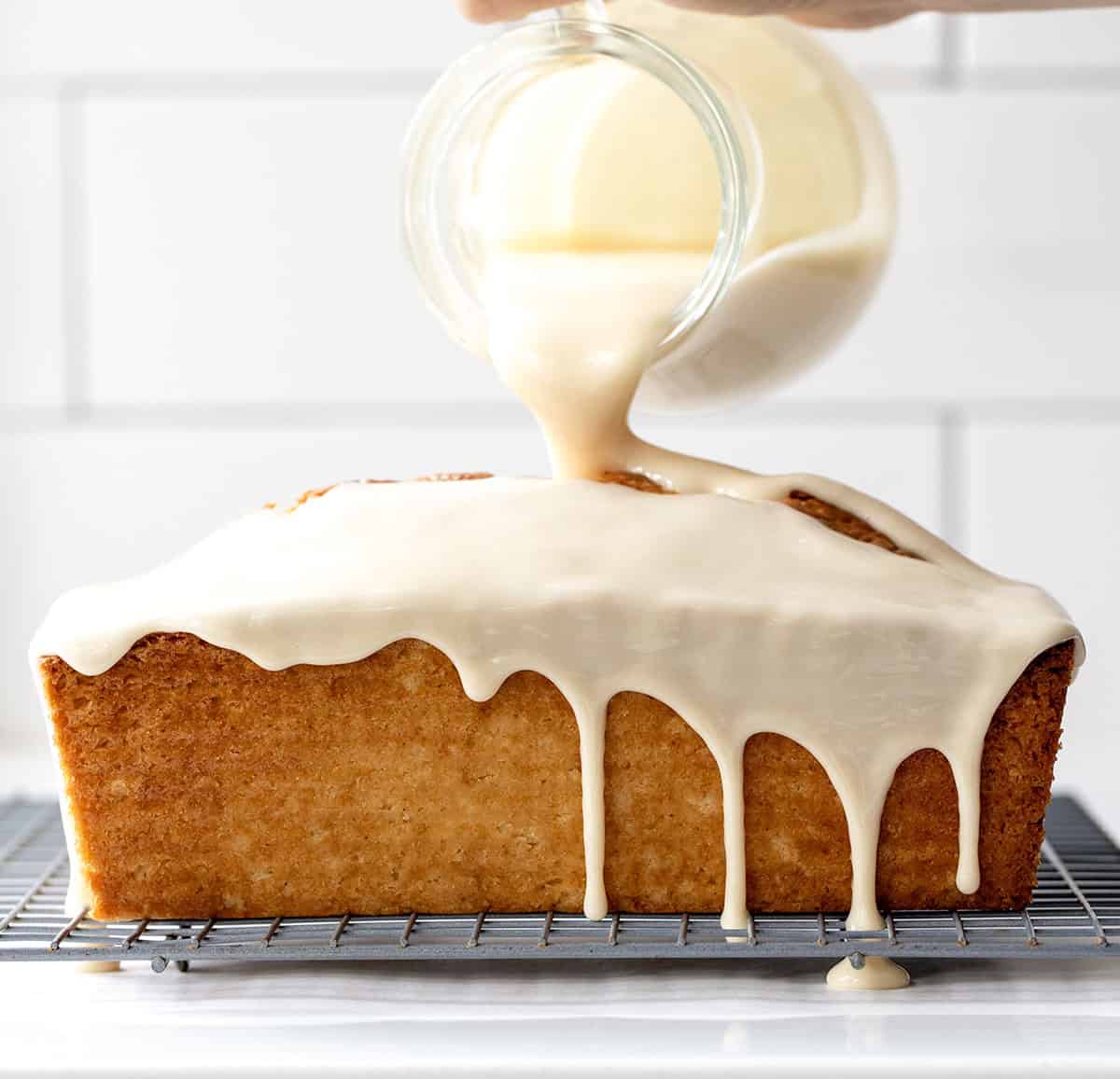Pouring maple glaze over donut bread loaf.