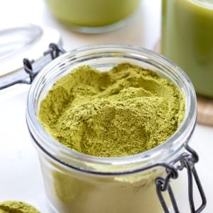 Matcha Latte Mix in front of an Iced Matcha Latte and a hot Matcha Latte on a white table.