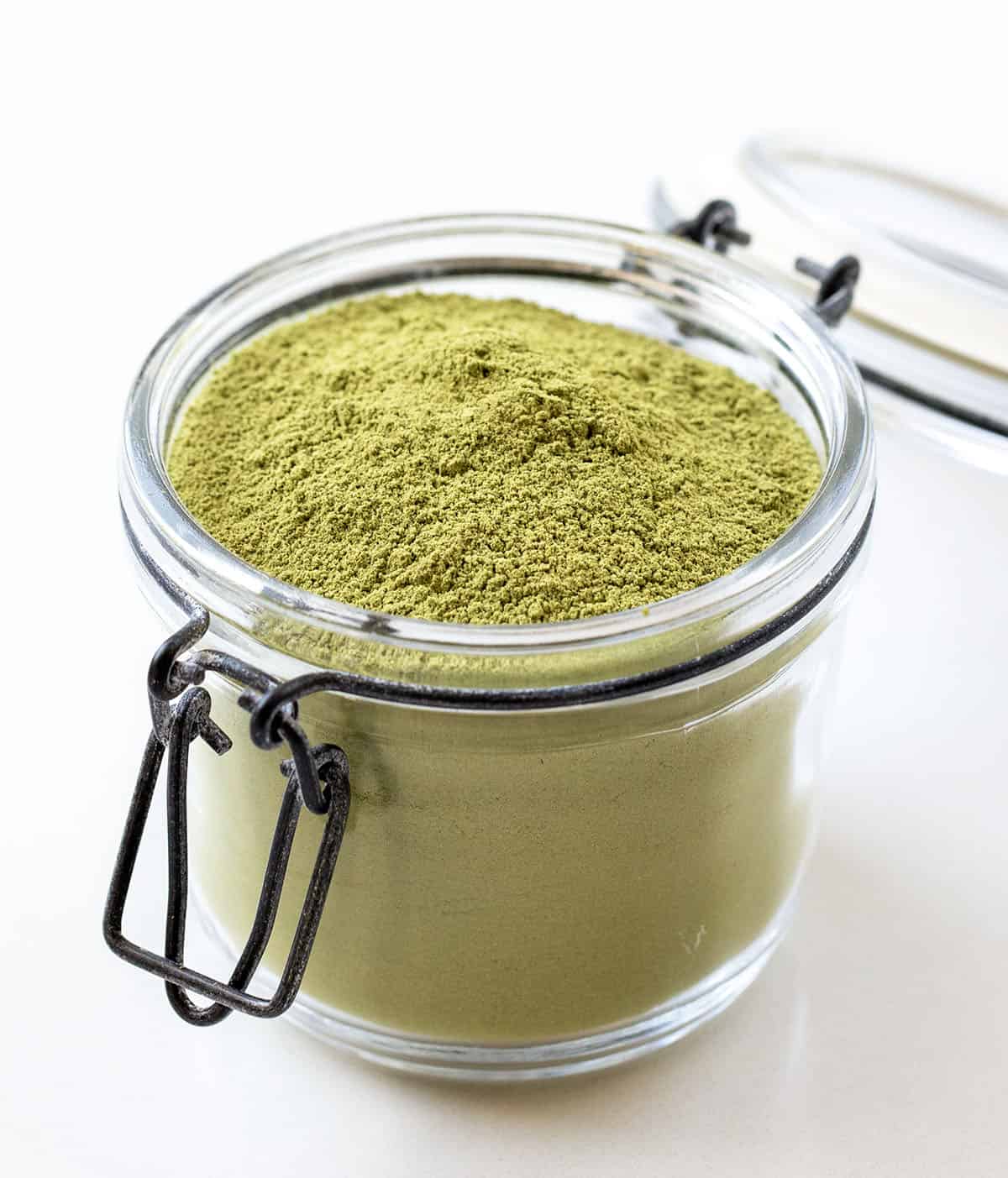 Jar of Matcha Latte Mix on a white table Jar of Matcha Latte Mix on a white table.