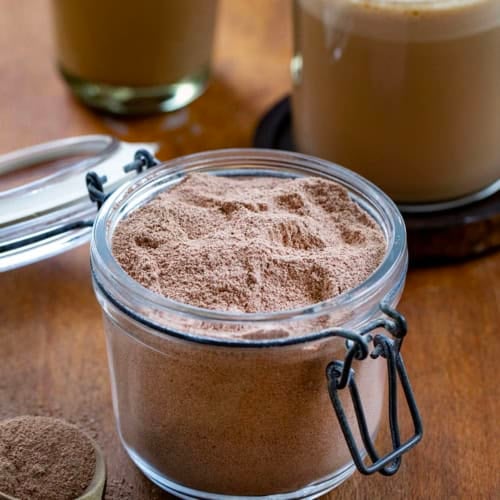 Jar of Mocha Latte Mix with an iced mocha latte and a hot mocha latte prepared int he background