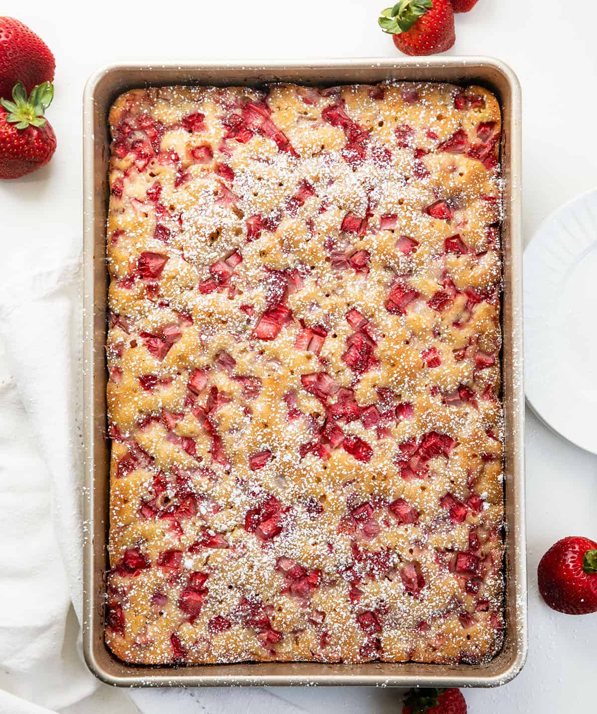 Old Fashioned Strawberry Sheet Cake in a pan on a white table from overhead.