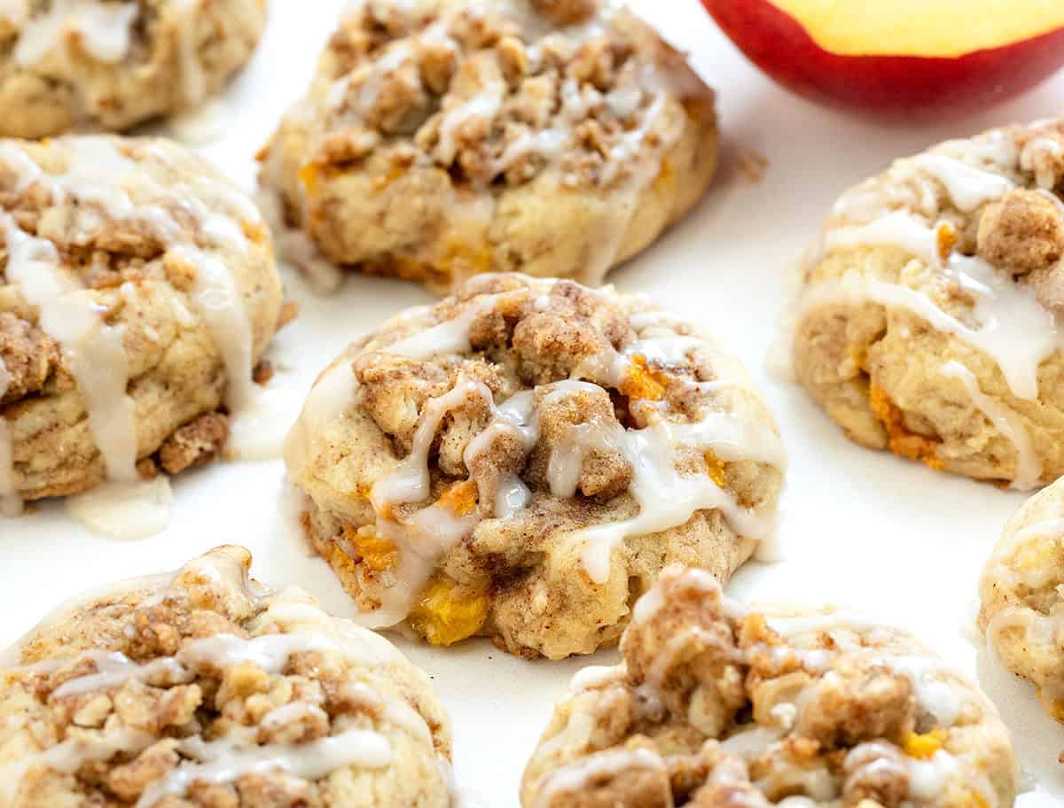 Close up of Peach Crisp Cookies on a white table with fresh peach.