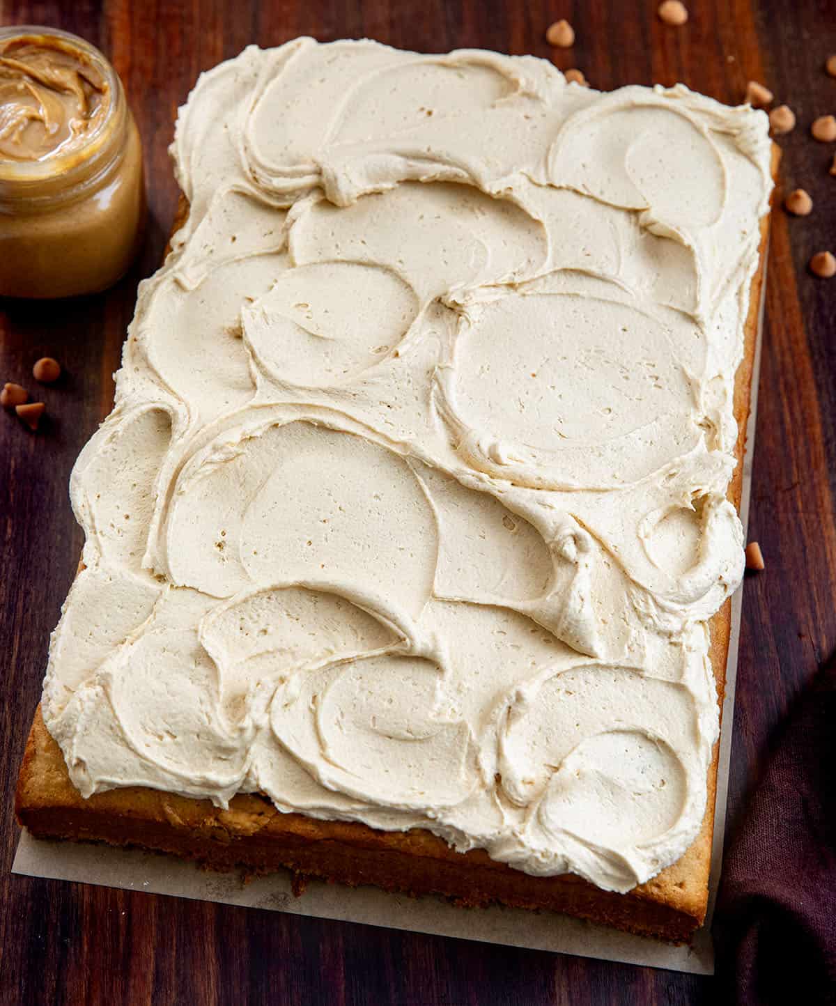 Frosted Peanut Butter Sheet Cake on a wooden table from overhead Frosted Peanut Butter Sheet Cake on a wooden table from overhead.