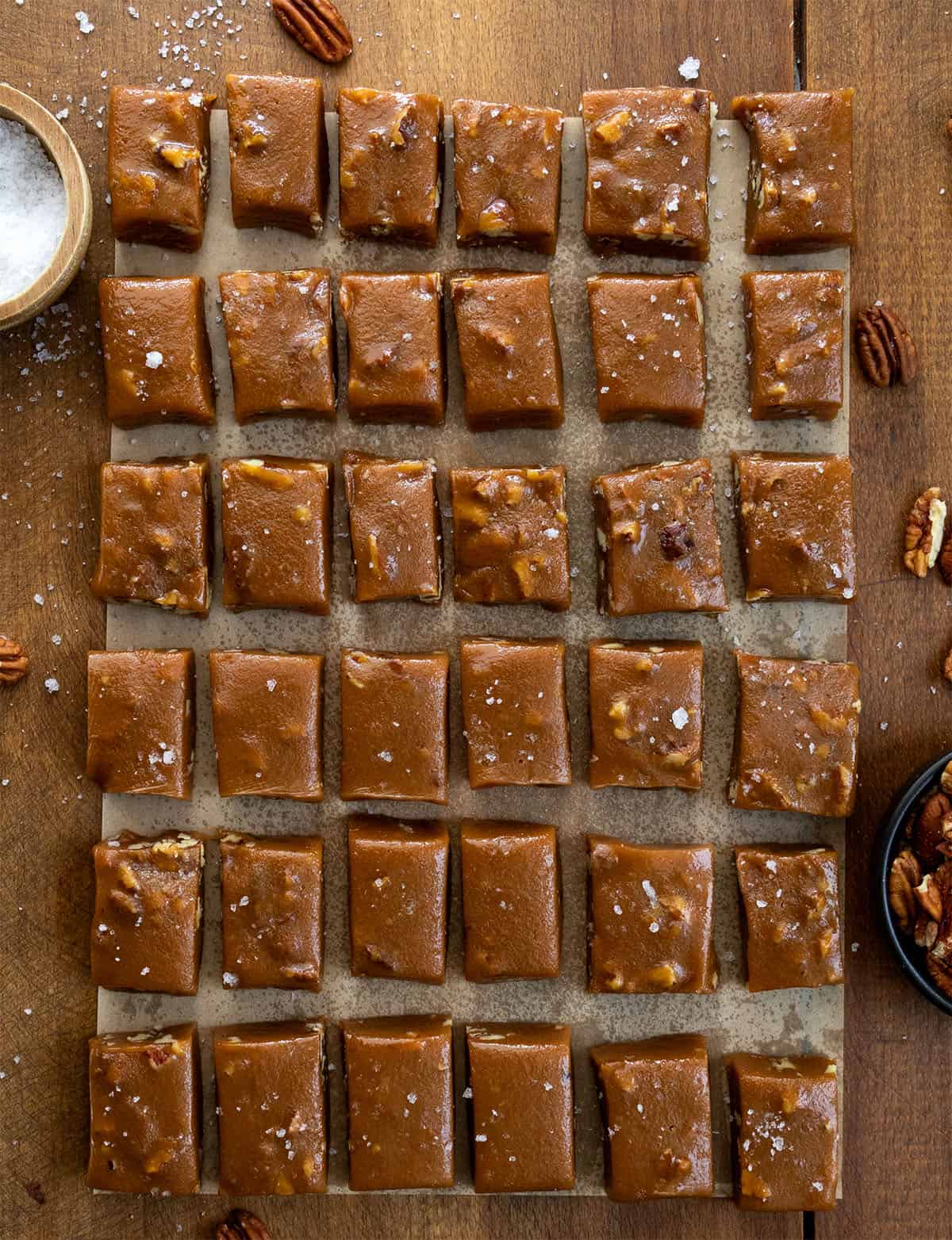 Soft Salted Pecan Caramels cut into squares on a wooden table.