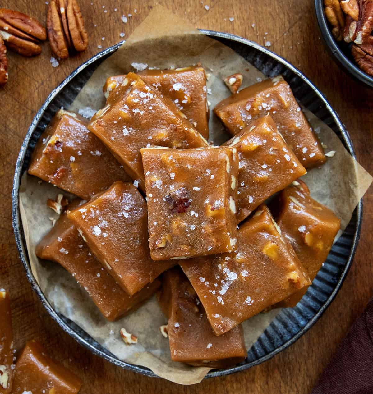 Plate of Soft Salted Pecan Caramels cut into squares on a wooden table from overhead.