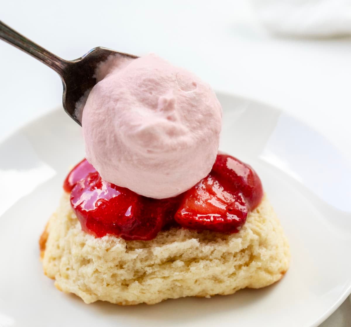 Adding Strawberry Stabilized Whipped Cream to a biscuit.