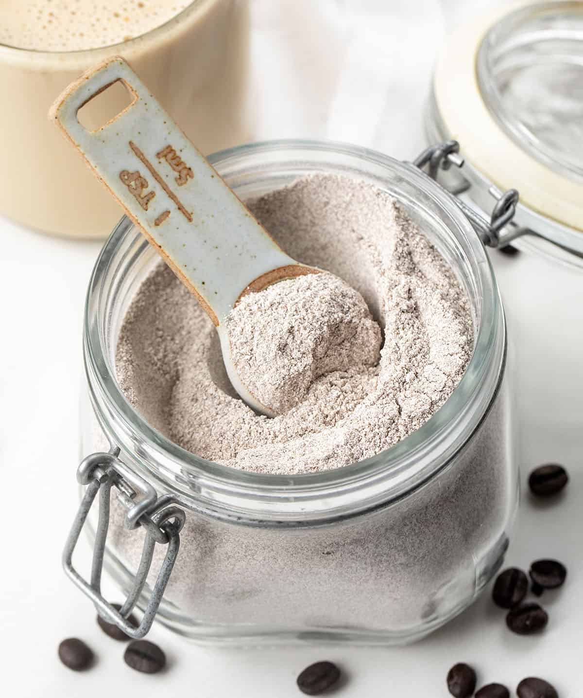 Glass jar of Vanilla Latte Mix on a white table with a mug of Vanilla Latte in the background Glass jar of Vanilla Latte Mix on a white table with a mug of Vanilla Latte in the background.