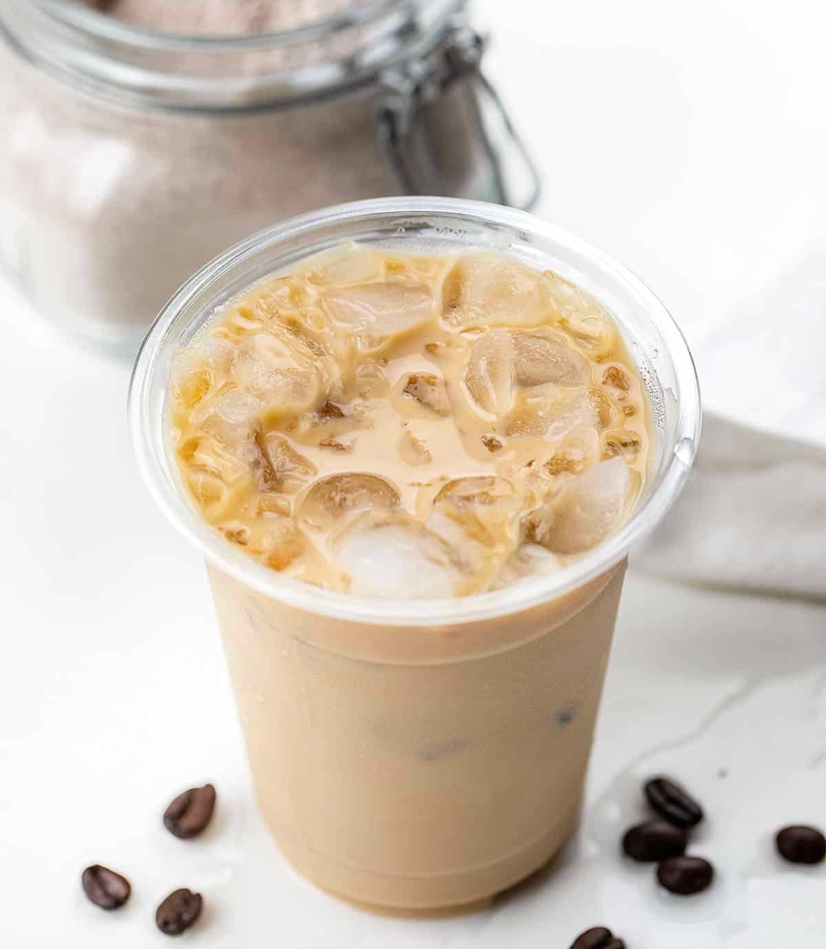 Iced Vanilla Latte on a white table in front of a jar of Vanilla Latte Mix Iced Vanilla Latte on a white table in front of a jar of Vanilla Latte Mix.
