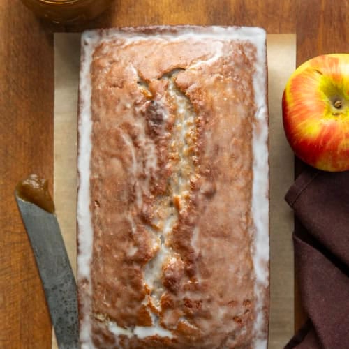 Glazed Apple Butter Bread on a wooden table with apple butter and an apple from overhead.