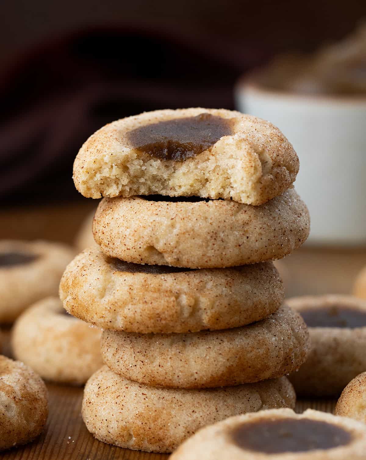 Stack of Apple Butter Thumbprint Cookies with the top cookie bitten showing inside texture.
