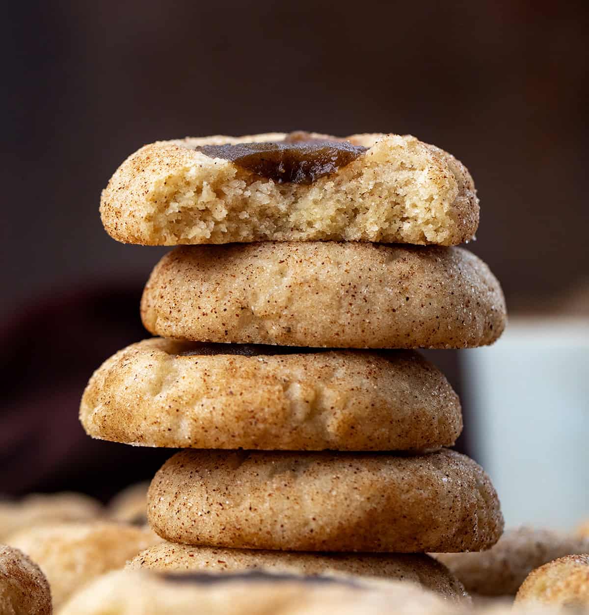 Small stack of Apple Butter Thumbprint Cookies with the top cookie having a bite taken out of it.
