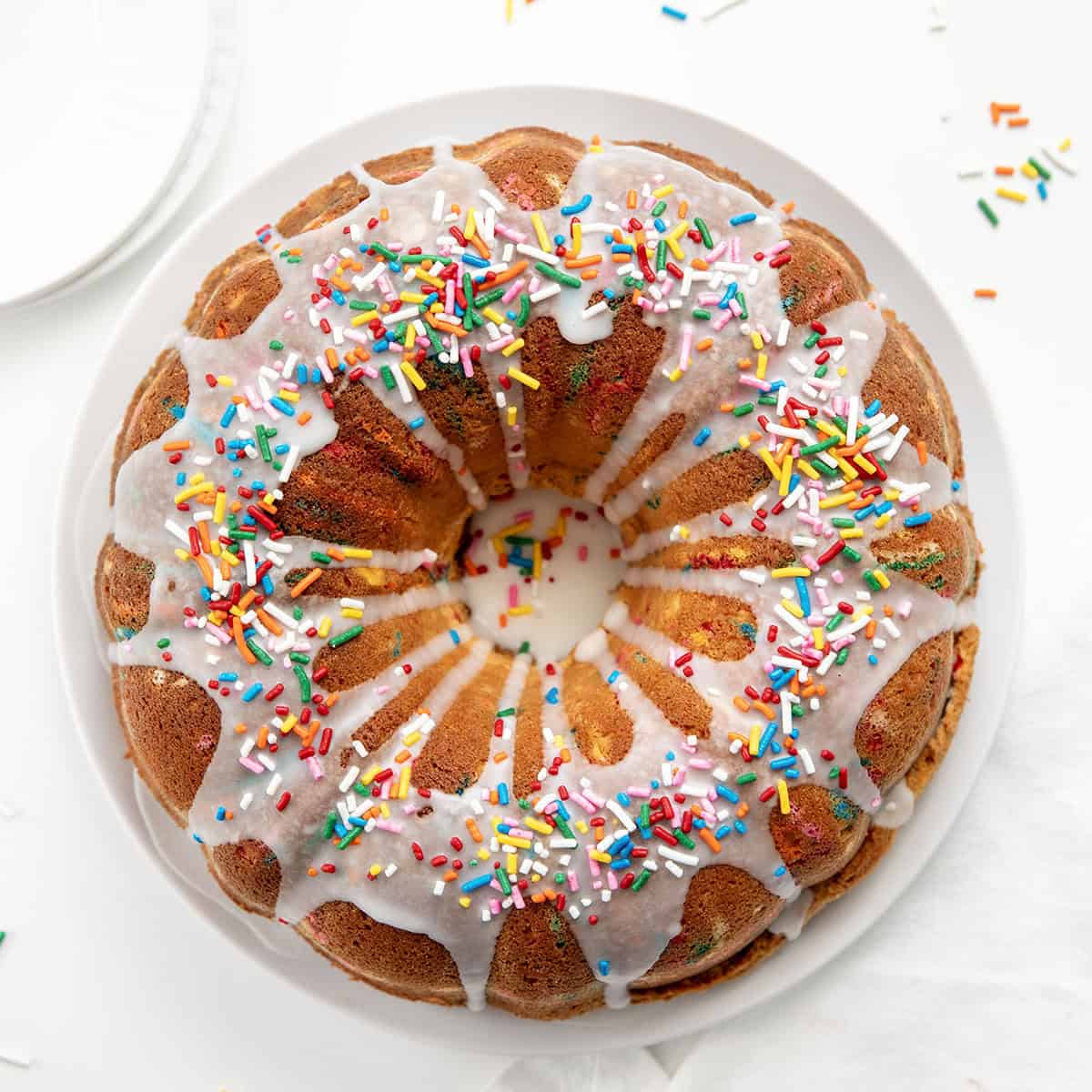 Whole Birthday Pound Cake on a white cake plate on a white table from overhead Whole Birthday Pound Cake on a white cake plate on a white table from overhead.