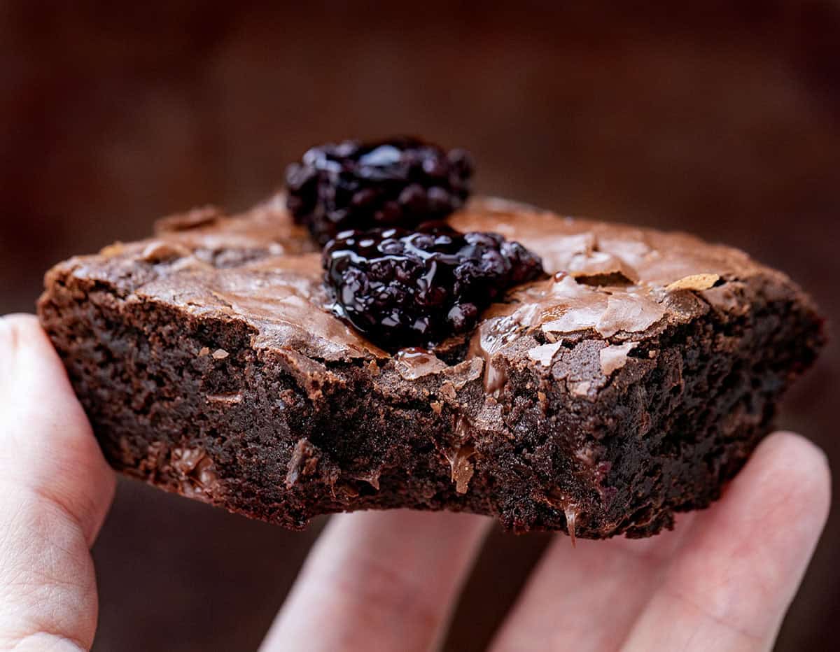 Hand holding a bit into Blackberry Balsamic Brownie Hand holding a bit into Blackberry Balsamic Brownie.