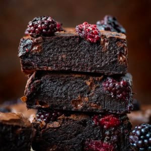 Stack of Blackberry Balsamic Brownies on a wooden table close up.