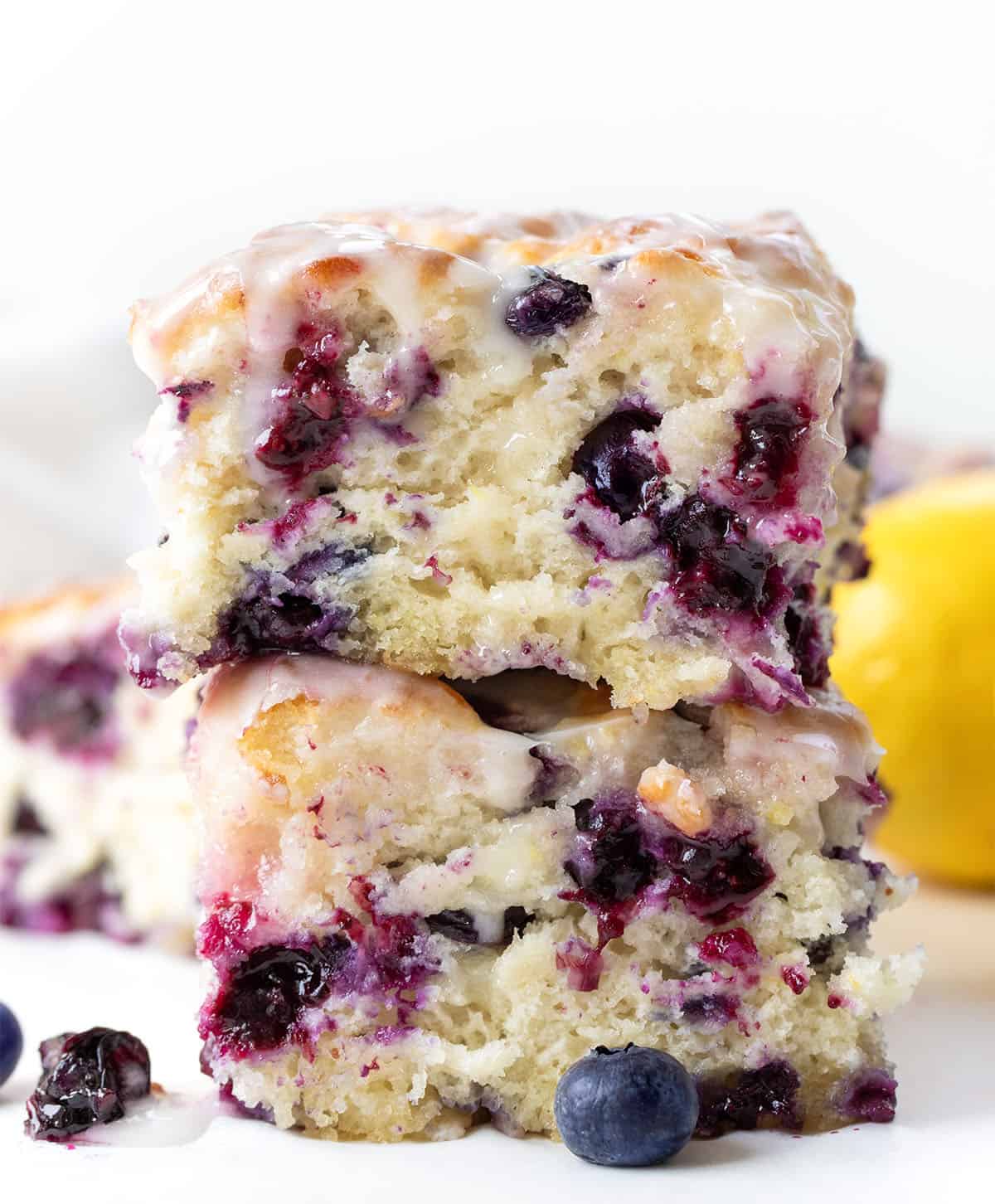 Stack of Blueberry Lemon Butter Swim Biscuits on a white table with lemon and blueberry.
