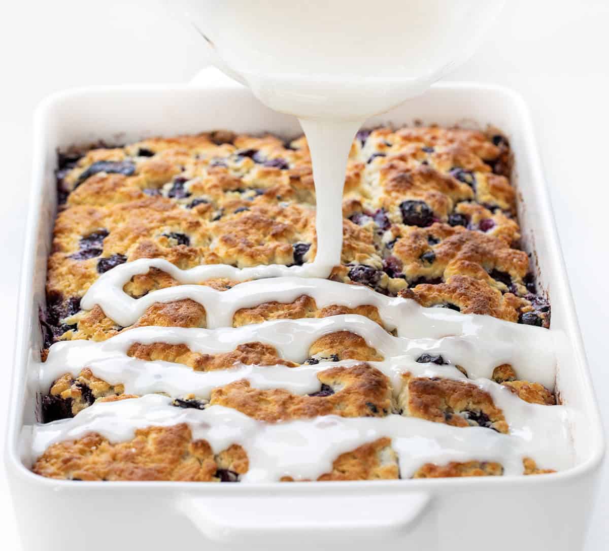 Drizzling glaze over Blueberry Lemon Butter Swim Biscuits.