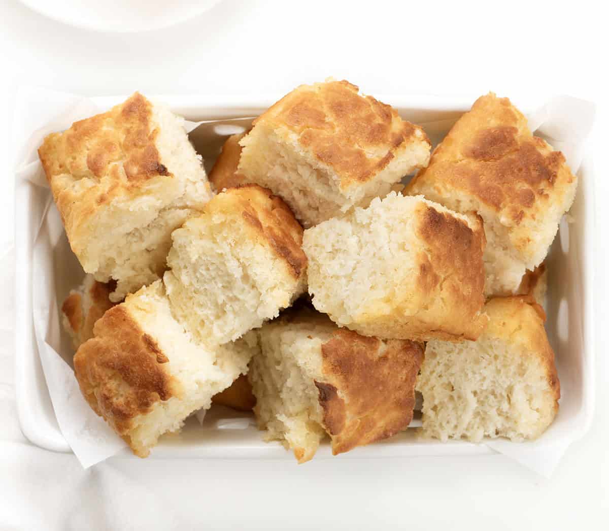 Basket of Butter Swim Biscuits for a Crowd on a white table from overhead.
