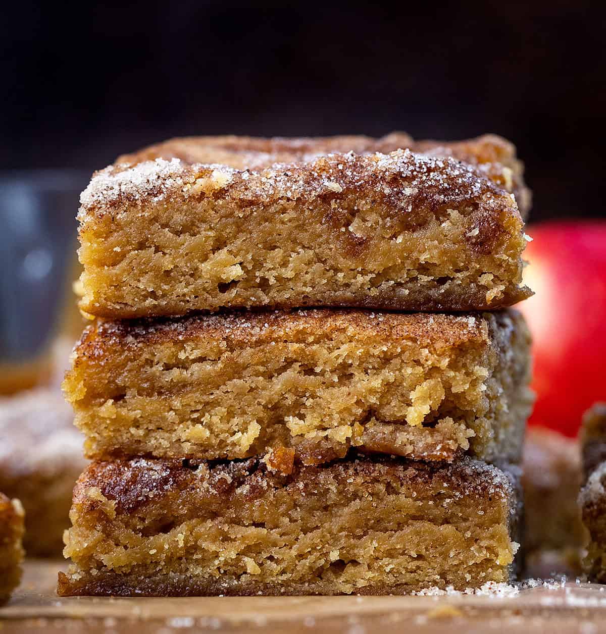 Stack of Caramel Apple Cider Blondies on a wooden table surrounded by caramel, apples, and more blondies Stack of Caramel Apple Cider Blondies on a wooden table surrounded by caramel, apples, and more blondies.