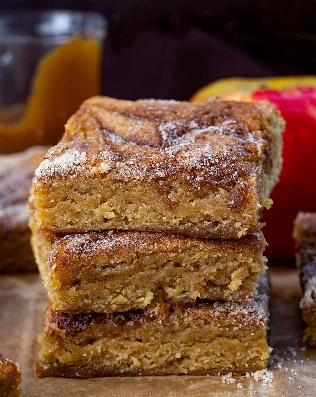 Stack of Caramel Apple Cider Blondies on a wooden table surrounded by caramel, apples, and more blondies Stack of Caramel Apple Cider Blondies on a wooden table surrounded by caramel, apples, and more blondies.
