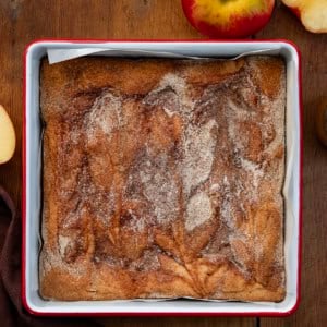 Pan of Caramel Apple Cider Blondies on a wooden table with fresh apple.
